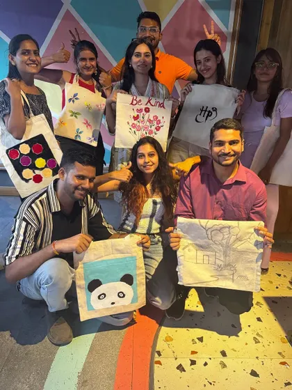 A group proudly displaying the tote bags they painted. Everyone leaves with a unique, personalized creation.