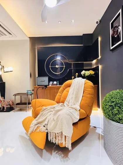 A wider view of the studio and lounge area, showcasing the eclectic mix of modern furniture, including a sculptural floor lamp and a comfortable orange lounge chair.