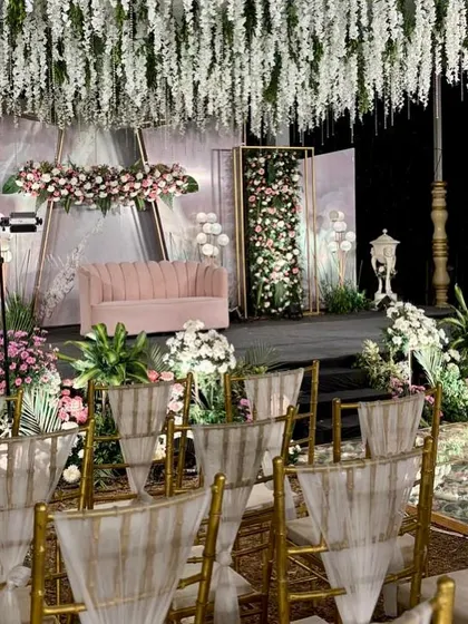 A view from the guest seating at a beautiful pastel reception, showing the elegant chairs and the stunning floral stage.