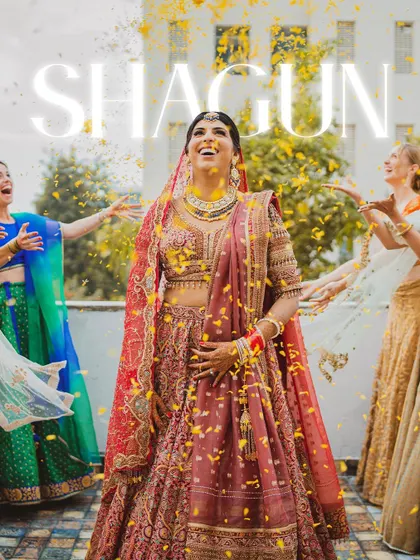 A moment of pure bridal bliss. The bride, Shagun, looks up with a joyful smile as her bridesmaids shower her with flower petals.
