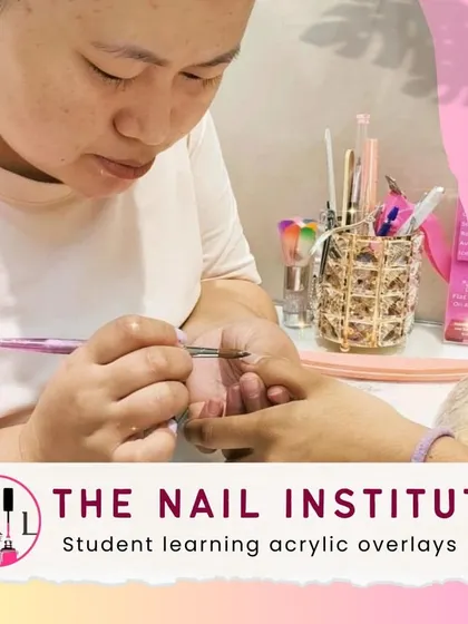Here, a student is practicing acrylic overlays, learning how to create a thin, durable layer over the natural nail.