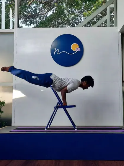 The chair is a versatile prop for building strength for advanced poses. Here, a practitioner uses it to support the hips while practicing the alignment for Mayurasana, or Peacock Pose, a challenging arm balance.