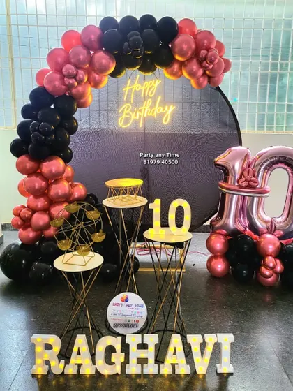 A 10th birthday party with a black and chrome-rose-gold balloon arch, neon sign, and matching number bouquet.