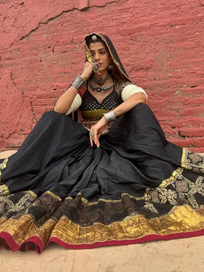 A dramatic and earthy look for Navratri. The black ghagra with a wide gold border is paired with a traditional blouse and heavy silver jewellery, creating a powerful, goddess-like image.