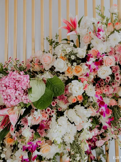 A vibrant and dense floral arrangement, featuring a beautiful mix of pink lilies, roses, and hydrangeas.
