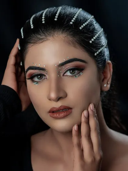 Another angle of this stunning creative makeup. The pearl hair accessories and face gems catch the light beautifully, showing the intricate detail of the work.