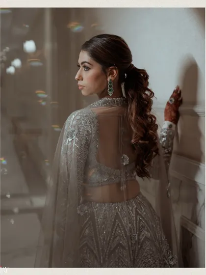 A beautiful shot of the bride from the back, showing off her hairstyle and the sheer cape of her Sangeet lehenga.