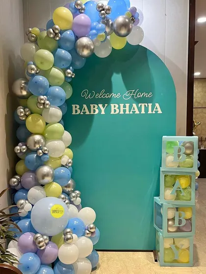 A modern and cheerful baby welcome for Baby Bhatia. The teal backdrop with a pastel balloon arch and matching "BABY" blocks adds a pop of color to the home.