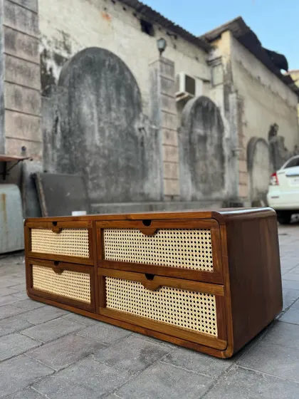 A low-profile chest of drawers with a teak frame and four cane-fronted drawers. This versatile piece can be used as a media console or for storage in a bedroom.