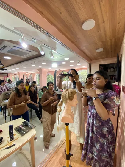 A trainer demonstrating a hairstyling technique while students observe and record for future reference.