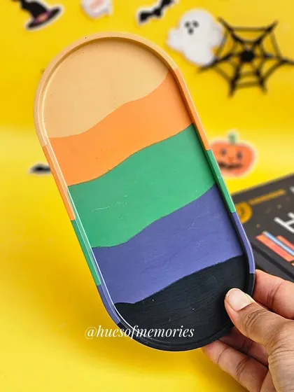 Holding up the Halloween palette oval tray to show off its vibrant, hand-painted stripes.