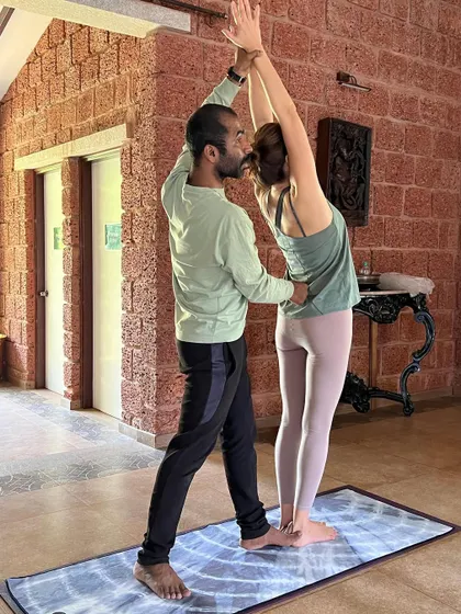 A hands-on adjustment for a standing backbend. Physical adjustments take practice and a deep understanding of asana anatomy, which is the core focus of our teacher development programs.
