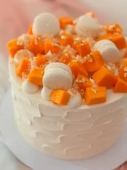 A close-up of the delicious mango cake, showing the juicy mango pieces, white macarons, and crumble topping.