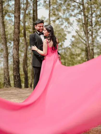 The vibrant pink of the bride-to-be's flowing gown creates a stunning visual against the earthy tones of the forest. This shot is a perfect example of a dramatic and colorful pre-wedding portrait.