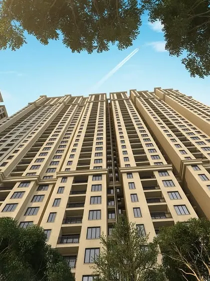 A worm's-eye view of the towering Casagrand Sun City, emphasizing the verticality and scale of the development while being framed by the natural canopy of trees.
