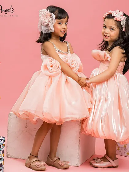 Two little angels holding hands, showcasing different styles from our party dress collection.