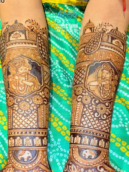 A close-up of the forearm work from a spiritual-themed bridal mehndi. This shows the intricate portraits of Lord Krishna playing his flute and Meera Bai in devotion, surrounded by traditional Indian architectural motifs.