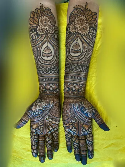 This design features beautiful jhumka (bell) elements within ornate arches on the forearms, complemented by floral patterns on the palms.