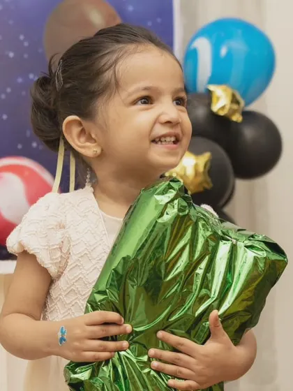 The birthday girl's happy smile as she holds a gift. This portrait captures the excitement and joy of a child on their special day.