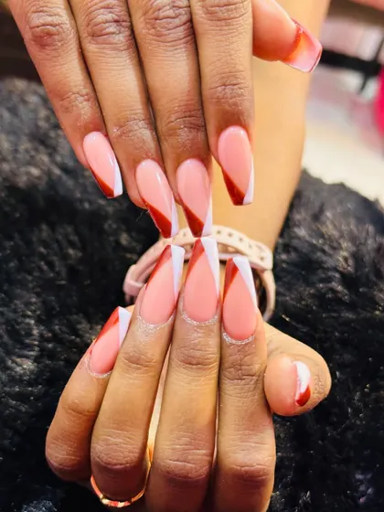 A sharp and geometric take on the French manicure. This V-shaped design, also known as a chevron tip, uses a bold red and crisp white line to create a modern and eye-catching look on long coffin nails.