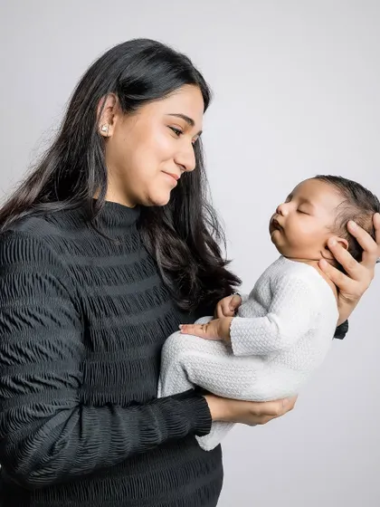 A mother gazes lovingly at her newborn, held securely in her arms.