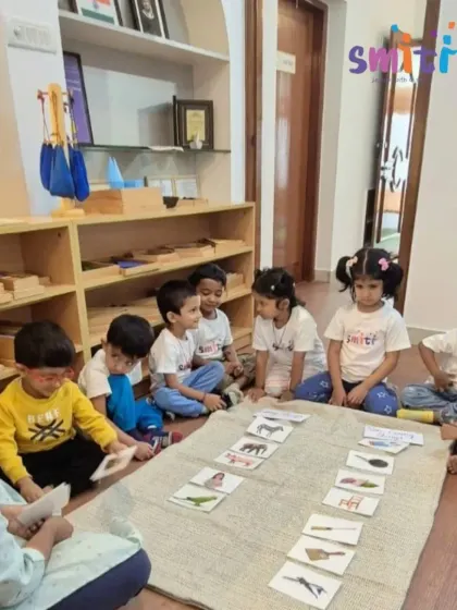 A teacher sits with a group of first-year children for a lesson on living and non-living things. Using picture cards, she guides a discussion that sparks their curiosity about the natural world.