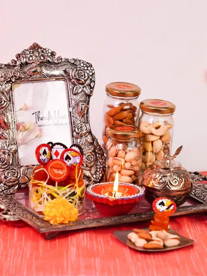 This Diwali hamper is a perfect example of thoughtful gifting. It combines jars of premium dry fruits with a decorative diya and an ornate silver photo frame, blending delicious treats with a lasting keepsake.