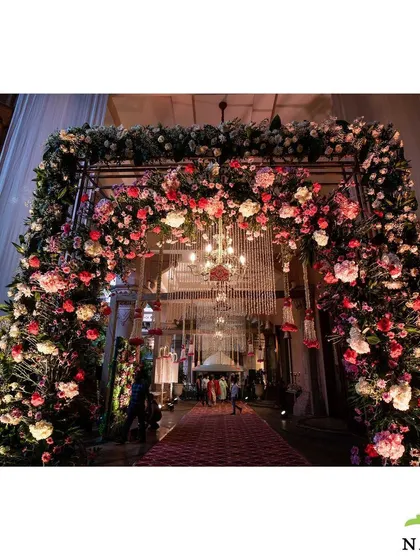 A grand floral archway serves as a stunning entrance. The structure is densely packed with pink and white roses, creating a luxurious and romantic welcome for guests.