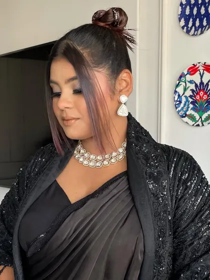The glitter top knot paired with soft, face framing pieces gives a modern and trendy feel to this look. The pink streaks in her hair add another fun element.