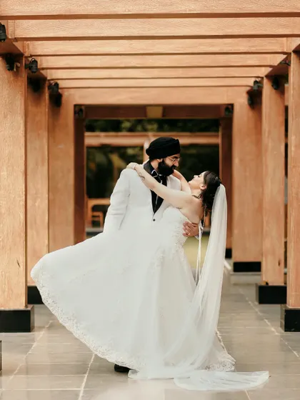 A joyful, dynamic shot of the groom lifting his bride as they dance, her veil flowing beautifully.