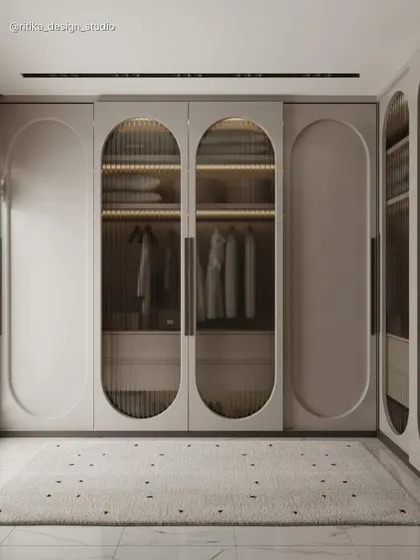 This image highlights a bespoke walk-in wardrobe I designed to blend elegance with functionality. The use of fluted glass in the arched doors offers a glimpse of the organized interior while maintaining a sense of privacy, and integrated lighting turns clothing storage into a beautiful display.
