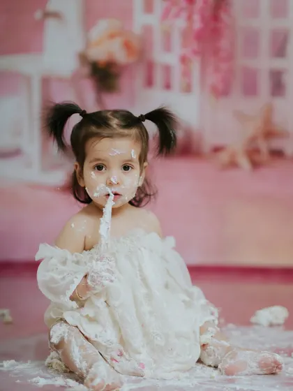 Another angle of her enjoying the cake, showing the soft, pretty details of the studio setup in the background.