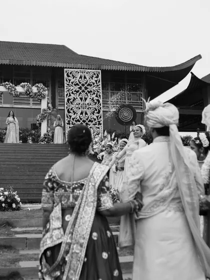 A black and white shot from the perspective of the family, watching the couple during their grand wedding ceremony. It highlights the importance of family in the celebration.