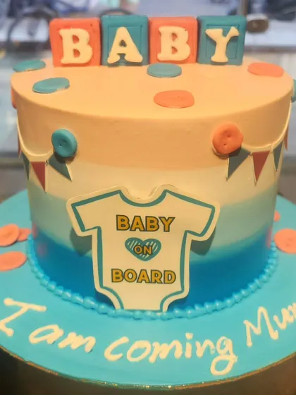 A sweet cake to celebrate a new arrival. This "Baby on Board" cake is perfect for a baby shower, with its gentle color gradient, baby blocks, and an adorable onesie design.