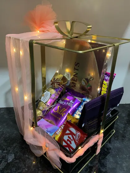 You can never go wrong with a classic chocolate hamper. This elegant metal bow basket is overflowing with a variety of favorites, including Ferrero Rocher, Cadbury Silk, and KitKat, making it an ideal gift for any celebration or just because.