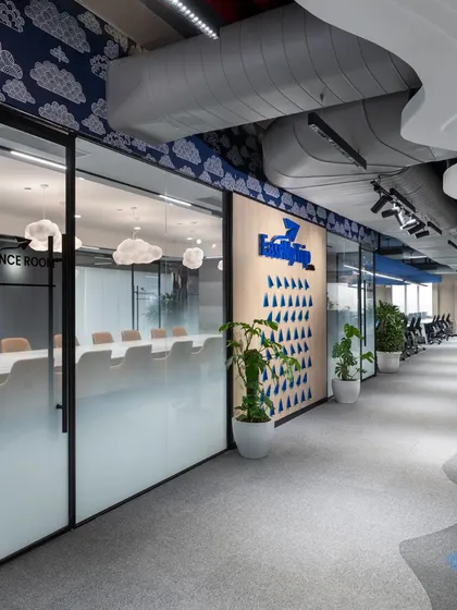 The hallway view into the conference room reveals how the space integrates with the rest of the office. Glass walls maintain a sense of openness, while frosted lower panels provide privacy for meetings.
