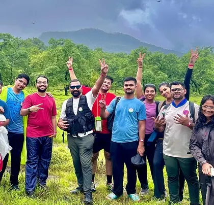 Another happy group celebrating the completion of the Dudhsagar trek, with the lush green hills of the Western Ghats behind them.