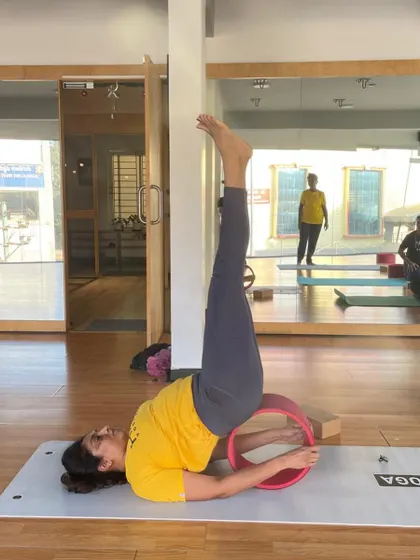 A student practices a supported shoulder stand on the wheel, a pose that is both restorative and strengthening.