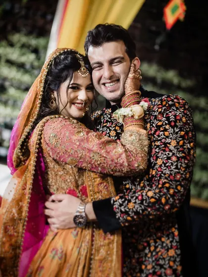 The vibrant colors and joyful energy of a Mehendi ceremony are on full display in this happy couple's portrait. It's a beautiful capture of a North Indian pre-wedding celebration.