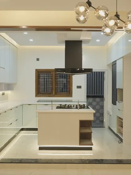 This gorgeous island kitchen features all-white, high-gloss handleless cabinets for a super sleek and luxurious feel. The glass breakfast bar on the island adds a touch of modern elegance.