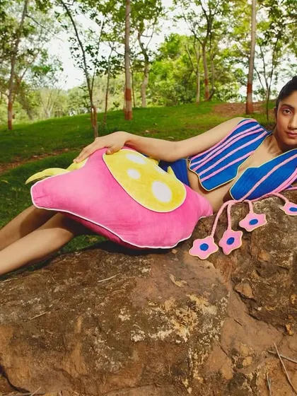 An outdoor campaign shot for the fashion label Sazo.in, featuring a model in a vibrant, playful outfit reclining on a rock in a lush, natural setting. This image demonstrates my ability to create a distinctive mood for brand lookbooks.