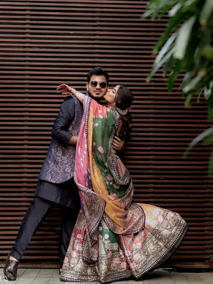 A playful and dramatic shot of the bride kissing the groom's cheek during their Mehendi carnival.
