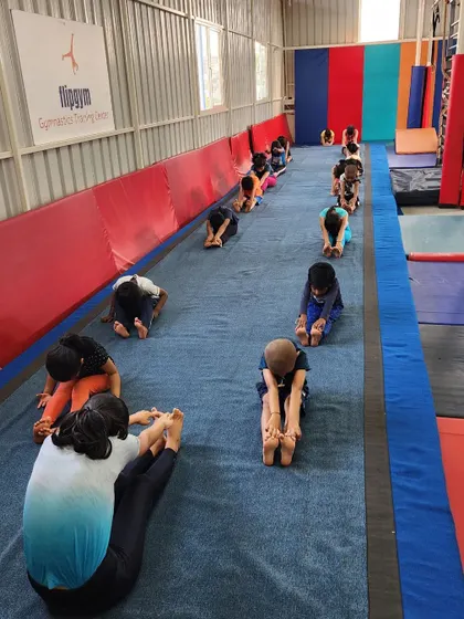 The seated forward fold is a classic stretch for the hamstrings and lower back, essential for many gymnastics skills.