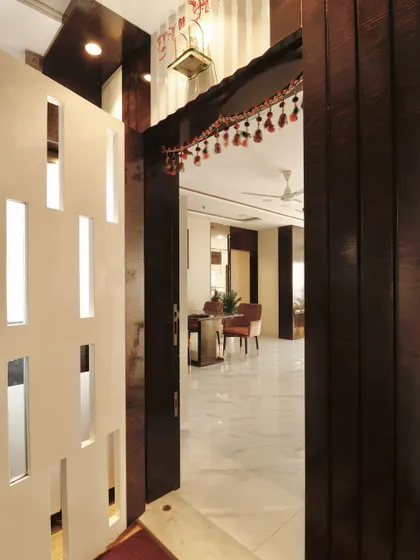 An inviting view from the entrance into the home, framed by dark wood paneling. The safety door has vertical frosted glass inserts, allowing light to filter through while maintaining privacy.