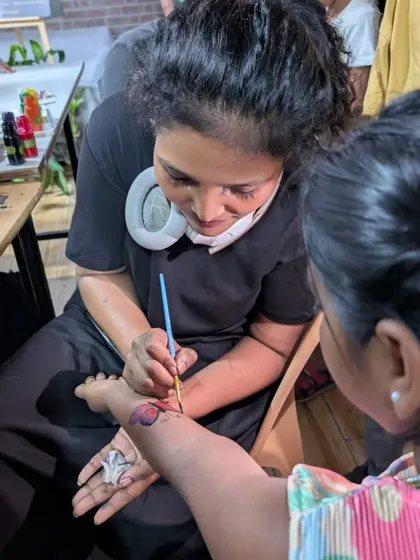 An artist carefully paints a butterfly on a young girl's arm. These little touches make our adoption drives a community event that people look forward to.