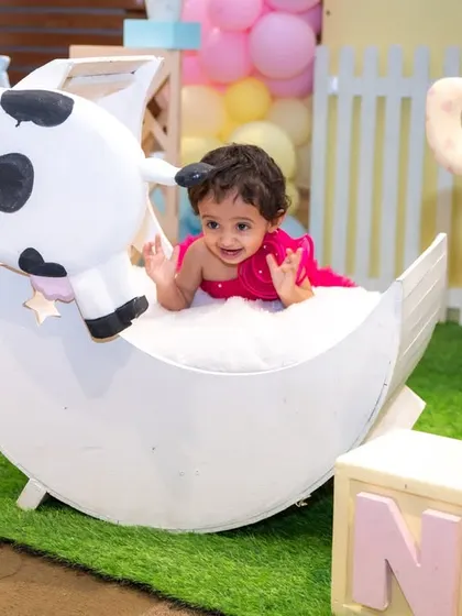 A joyful shot of a baby girl playing in a prop at her farm-themed first birthday party. Our photography captures the fun and interactive elements of your child's celebration.