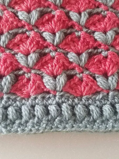 A close-up of my Cardamom Blossoms cowl, showing the textured stitch pattern in pink and grey. This stitch creates a thick, squishy fabric that is incredibly warm.