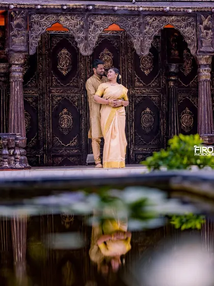 A stunning reflection shot of a couple in traditional attire. The calm water creates a perfect mirror image, adding an artistic touch to this elegant portrait.