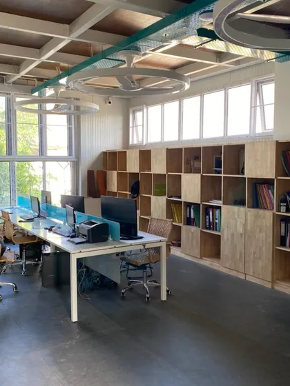 The upper-level workstation area in our studio, featuring custom wooden shelving for storage. The exposed ceiling and custom ring-fan lights contribute to the space's modern, industrial aesthetic.