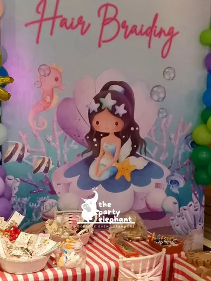 The hair braiding station, complete with a themed backdrop and bowls of colorful accessories for creating mermaid-inspired hairstyles.